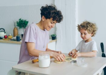 Young family mother and son making home-made cookies at kitchen table