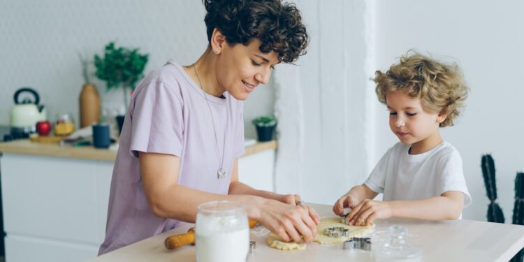 Young family mother and son making home-made cookies at kitchen table