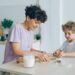 Young family mother and son making home-made cookies at kitchen table