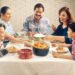 Family Eating Meal. A Hispanic family (male adult, two female adults, female child, and male child) enjoy a meal at the dinner table.