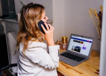 Vrouw aan een bureau met laptop en telefoon