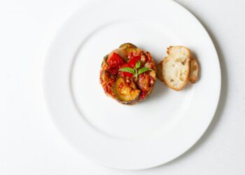 Geroosterde plakken aubergine met tomatensaus en feta in een ovenschaal
