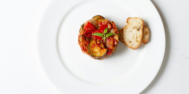 Geroosterde plakken aubergine met tomatensaus en feta in een ovenschaal