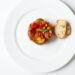Geroosterde plakken aubergine met tomatensaus en feta in een ovenschaal