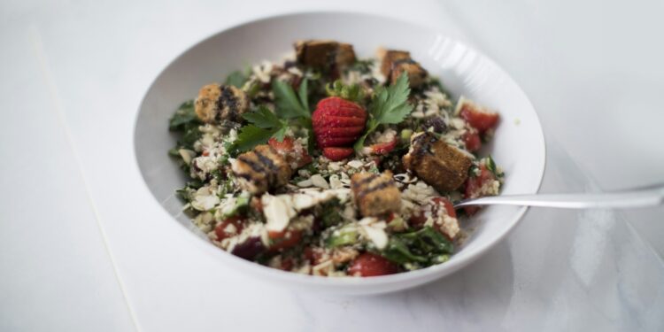 Schaal met parelcouscous, paprika en platgedrukte gehaktballetjes met yoghurtsaus