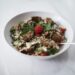 Schaal met parelcouscous, paprika en platgedrukte gehaktballetjes met yoghurtsaus