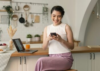 Vrouw bekijkt een verdacht betaalverzoek op haar telefoon aan de keukentafel