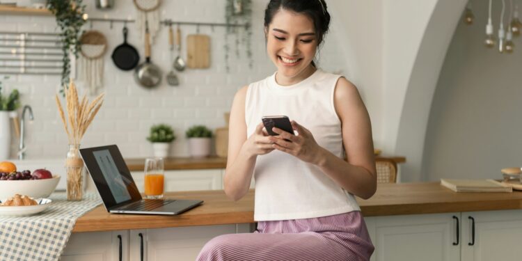 Vrouw bekijkt een verdacht betaalverzoek op haar telefoon aan de keukentafel