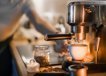 Koffiezetapparaat met glazen kan en een fles ontkalker op het aanrecht