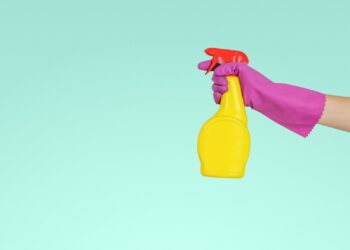Sprayfles met schoonmaakazijn naast een glazen douchewand met kalkvlekken