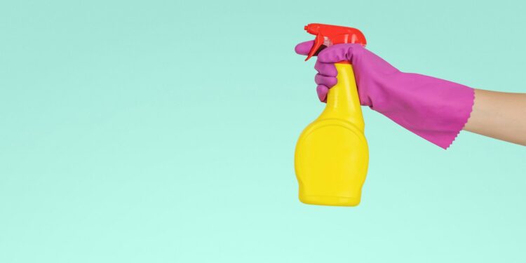 Sprayfles met schoonmaakazijn naast een glazen douchewand met kalkvlekken