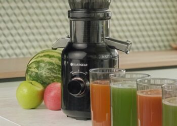 Zwarte Silvergear slowjuicer op een aanrecht met fruit en glazen vers sap