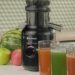 Zwarte Silvergear slowjuicer op een aanrecht met fruit en glazen vers sap