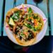 Zachte taco's gevuld met gekruid varkensvlees, zure room en een frisse salsa
