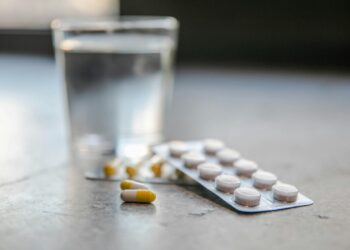 Vitaminepillen naast een glas water op een keukentafel bij het ontbijt