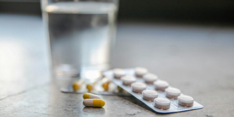 Vitaminepillen naast een glas water op een keukentafel bij het ontbijt