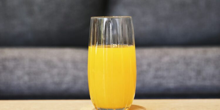 Glas verse wortelsap met wortels op een keukentafel