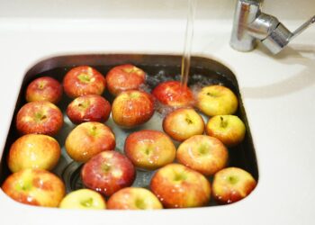 Rode en groene appels met schil in een vergiet onder de kraan