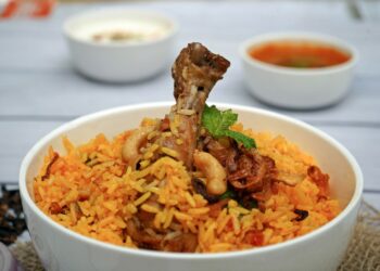 Pan biryani met lamsvlees, gele rijst, gebakken ui en verse koriander