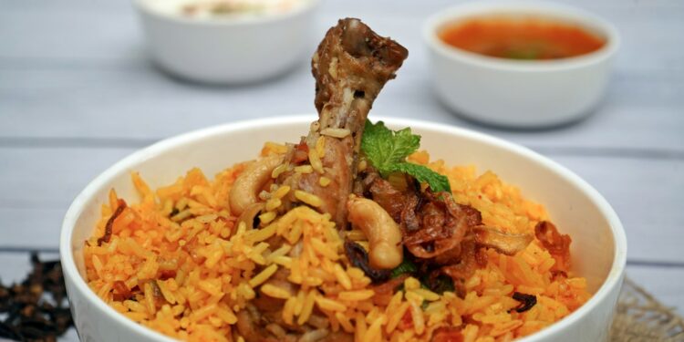 Pan biryani met lamsvlees, gele rijst, gebakken ui en verse koriander