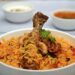 Pan biryani met lamsvlees, gele rijst, gebakken ui en verse koriander