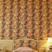 Muur met behang met grote botanische bladeren en bloemen achter een bed