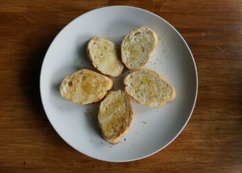 Crostini met gesmolten kaas, gekaramelliseerde ui en tijm op een plank