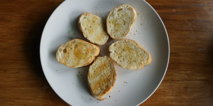 Crostini met gesmolten kaas, gekaramelliseerde ui en tijm op een plank