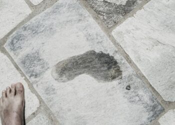 Natte voetafdruk op een stenen ondergrond naast een blote voet