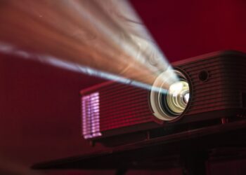 Projector die een film op een witte muur projecteert in een donkere woonkamer