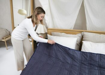 Opgemaakt bed met een elektrische onderdeken en bedieningsknop onder het hoeslaken