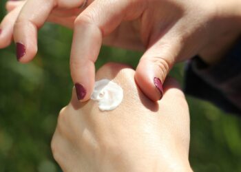Handen die handcrème uit een tube insmeren op een winterse dag