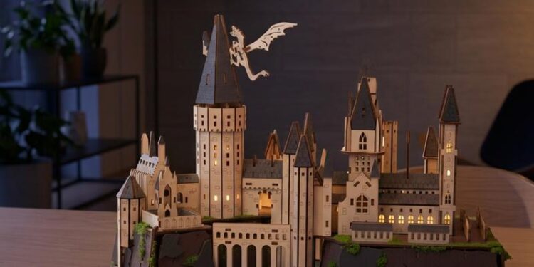 Houten 3D-puzzel van kasteel Zweinstein met verlichte ramen op een tafel