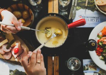Pan met gesmolten kaasfondue en stukjes brood op fonduevorkjes