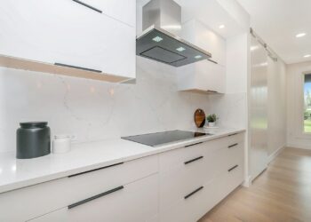 Lichte keuken met matzwarte greepjes, een zwarte kraan en ledverlichting onder de kastjes