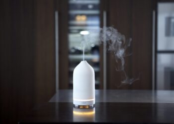 Witte keramische aromadiffuser met een wolkje nevel op een tafel
