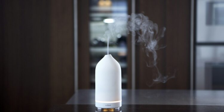 Witte keramische aromadiffuser met een wolkje nevel op een tafel