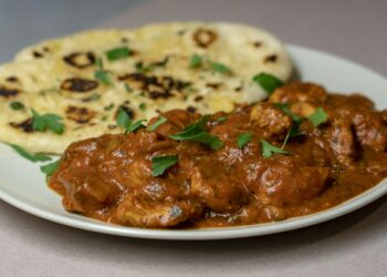 Kom romige pompoencurry met spinazie en naanbrood ernaast