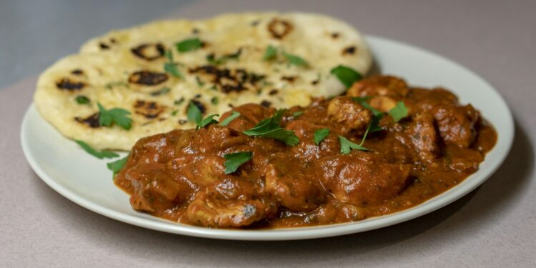 Kom romige pompoencurry met spinazie en naanbrood ernaast