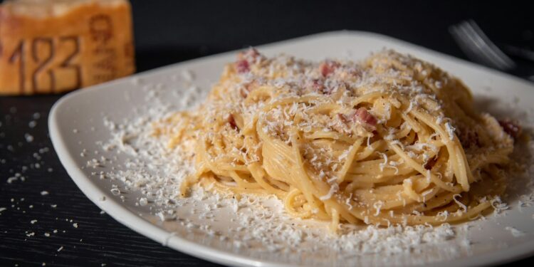 Bord spaghetti carbonara met spek en zwarte peper