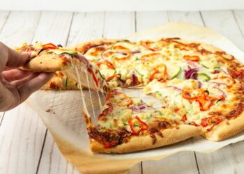 Versgebakken pizza met krokante bodem op een snijplank in een lichte keuken