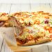 Versgebakken pizza met krokante bodem op een snijplank in een lichte keuken