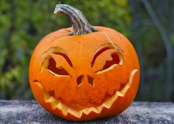 Uitgeholde Halloweenpompoen met gesneden gezicht op een stoep