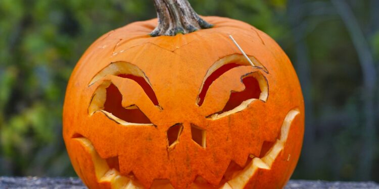 Uitgeholde Halloweenpompoen met gesneden gezicht op een stoep