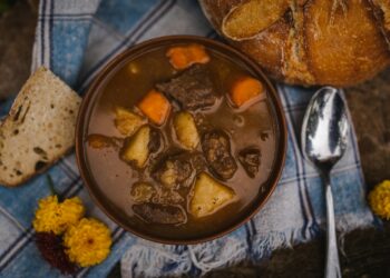 Pan met donker stoofvlees in biersaus op een houten tafel
