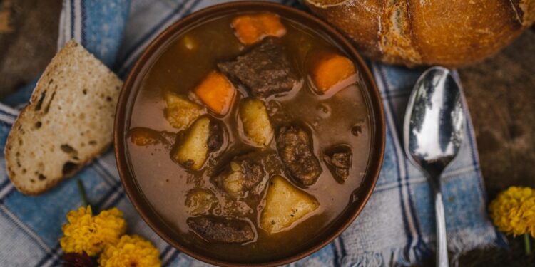 Pan met donker stoofvlees in biersaus op een houten tafel