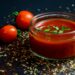 Tomatenpuree in een kommetje naast verse tomaten op het aanrecht
