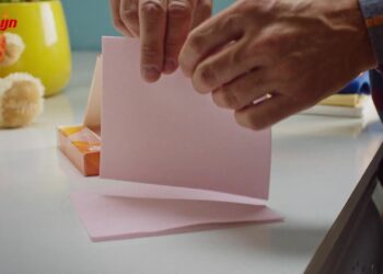 Hand scheurt een roze wasmiddeldoekje van Robijn doormidden boven de wasmachine