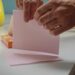 Hand scheurt een roze wasmiddeldoekje van Robijn doormidden boven de wasmachine