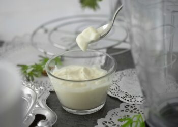 Glazen pot met zelfgemaakte yoghurt en een houten lepel op tafel